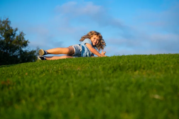 Un ragazzo che cade sull'erba. Il ragazzo che cade al parco. — Foto Stock