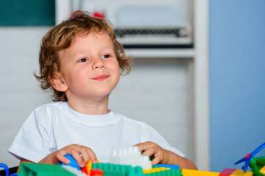 İlkokuldan bir çocuk. Çocuk anaokulundaki oyuncaklarla oynuyor..