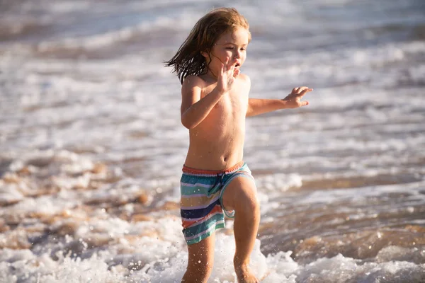 Un ragazzino che corre sulla spiaggia. Bambino felice correre in mare in vacanza estiva. Viaggi e avventure in mare o in mare. — Foto Stock