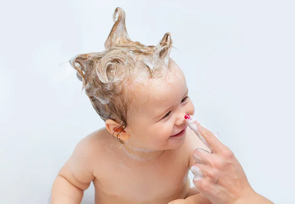Kinderbaden. Glückliches Baby, das ein Bad nimmt und mit Schaumblasen spielt. Kleines Kind in der Badewanne. Lächelndes Kind im Badezimmer mit Spielzeugente. Säuglingswäsche und Baden. Kinderpflege und Hygiene. — Stockfoto