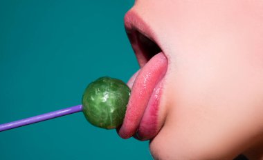 Kadın ağzında lolipop, kırmızı ruj. Kırmızı, parlak bir lolipopu yalayan bir kadın. Kapatın. Şehvetli ağzında lolipopu olan seksi kadın..