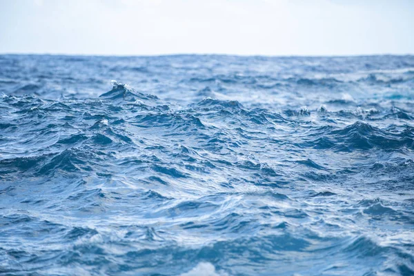 Moře abstraktní nebo zvlněné vody textury pozadí. Klidná textura vodní hladiny s cákáním a vlnami. Abstraktní příroda. Povrch modré oceánské vody. — Stock fotografie