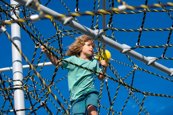 Little kid boy hanging on the monkey bar by his hand to exercise at outdoor playground. Rope Park. — Stock Photo, Image