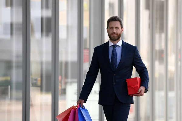 Uomo d'affari che tiene le borse della spesa e cammina in negozio. Shopping e pagamento. Shopaholic concetto di shopping. — Foto Stock