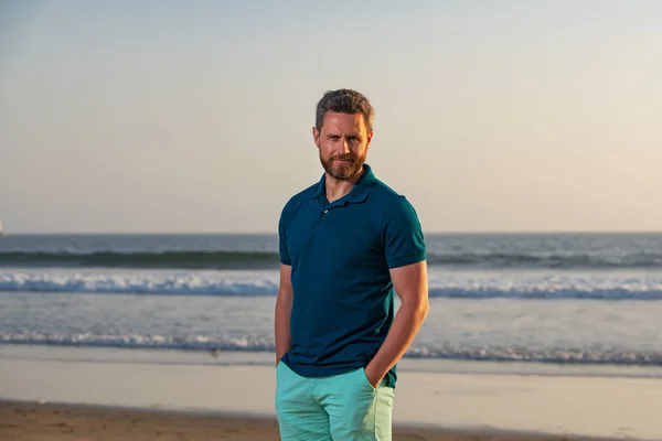 Retrato de homem na praia. Retrato de homem de meia-idade com uma expressão séria e fundo do oceano em pé na praia. — Fotografia de Stock