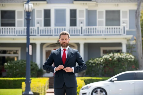 Fastighetsmäklare välkomnar besökare nära nytt hus. Porträtt av mäklare man. — Stockfoto