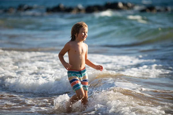 Niño saltando en olas marinas. Saltar por el agua salpicaduras de mar. Vacaciones de verano para niños. — Foto de Stock