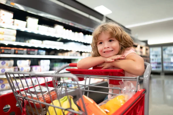 Bambino in drogheria o supermercato con merci nel carrello della spesa. Kid shopper con generi alimentari. — Foto Stock