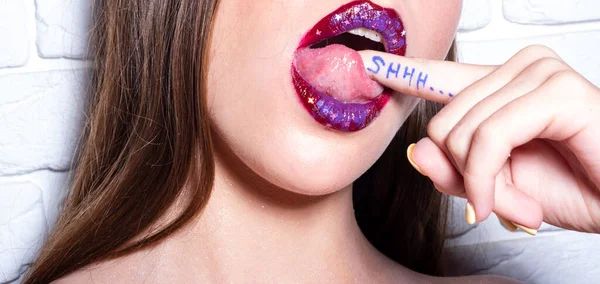 Shhh, vrouwen geheimen. Vrouw met vinger in sensuele mond. Stilte met shhh op de vinger geschreven. Sexy volle lippen. — Stockfoto