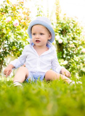 Panamalı bir çocuk. Yazlık kıyafetlerle yürüyorum. Bahar parkında ya da bahçede gülümseyen mutlu çocuk, bulanık arka plan.