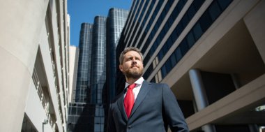 Yönetici işadamı. Modern ofis yakınlarında takım elbiseli bir CEO portresi. Şirket binasının önünde duran mutlu lider..