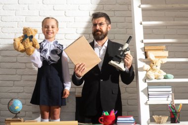 Öğretmen baba, yaratıcı kız çocuğuyla çalışıyor. Çocuk eğitimi, ilkokul ve öğrenme konsepti. Sınıftaki kız ve öğretmen..