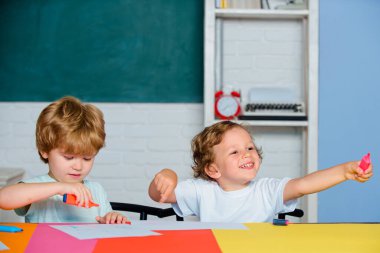 Neşeli gülümseyen çocuklar tahtaya tırmanıyor. İlkokuldan bir çocuk..