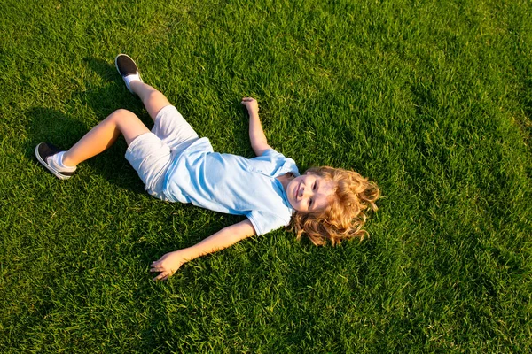 Счастливый улыбающийся мальчик отдыхает на траве. Вид сверху с пространством для копирования. — стоковое фото