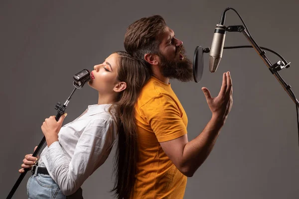 Guy a dáma s vzrušenými tvářemi mají rádi hudbu. Pár zpěváků z Karaoke. Muž a žena zpívající s hudebním mikrofonem. — Stock fotografie