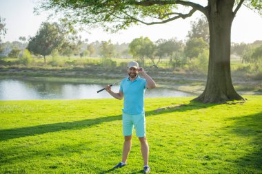 Profesyonel golf sahasında erkek golfçü. Golf sopalı bir golfçü ateş ediyor..