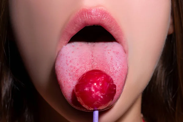 Γλειφιτζούρι στο στόμα της γυναίκας, κόκκινο κραγιόν. Γυναίκα γλείφει ένα κόκκινο γυαλιστερό γλειφιτζούρι. Κλείσε. Σέξι γυναίκα με γλειφιτζούρι στο σέξι στόμα. — Φωτογραφία Αρχείου