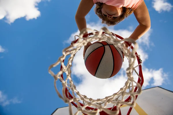 Utsikt över flygande boll till korg från toppen, unge spela basket. En liten pojke som spelar basket med basket. Aktiva barn livsstil. — Stockfoto