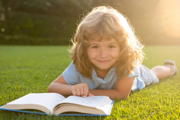 Kleine jongen leest een boek in de zomer zonsondergang licht. — Stockfoto