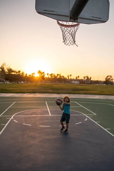 Basketbal kluk kluk trénink hra na západ slunce. — Stock fotografie