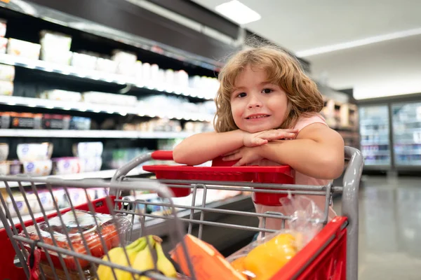 Miúdo com carrinho de compras numa mercearia. Compras de mercearia. — Fotografia de Stock