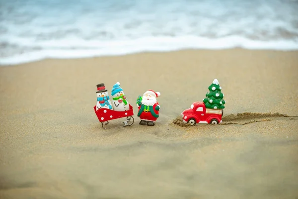 Giocattolo Babbo Natale sullo sfondo dell'oceano tropicale. Natale in vacanza calda. Clima caldo anno nuovo, tema per manifesti, biglietti di auguri. — Foto Stock