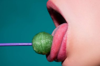 Ağız yalayan lolipop, kırmızı kadın parlak dudaklar ve pembe şeker lolipopu..