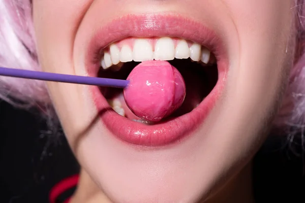 Sensual red lips with candy for print. Red lollipop in the mouth in art design. Glossy womans lips licking sucking lollipop. Sensual sexy mouth with candy concept enjoyment beautiful female lips.