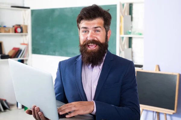 Leende lärare med bärbar dator anteckningsbok i klassrummet i skolan. Porträtt av rolig lärare i klassrummet. Fantastiska professorn väntar på studenter. Positiva uttryck känslor roligt ansikte. — Stockfoto