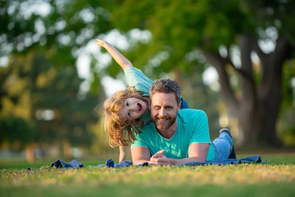 Glücklicher Vater und Sohn genießen den Sommerurlaub in einem sonnigen Park. Konzept von gesundem Urlaub und familiärer Aktivität. — Stockfoto