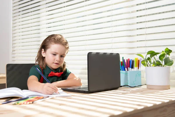 Malá studentka si dělá domácí úkoly s tabletem nebo notebookem doma. Žák zapíše úkol do zápisníku. Vzdělávání a učení pro chytré děti, domácí školní docházka. — Stock fotografie