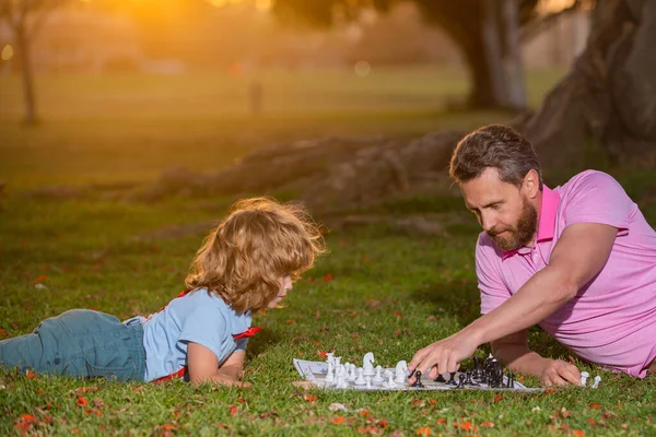 Padre e hijo jugando ajedrez pasando tiempo juntos al aire libre. Niño golpeando a un hombre en el ajedrez. — Foto de Stock