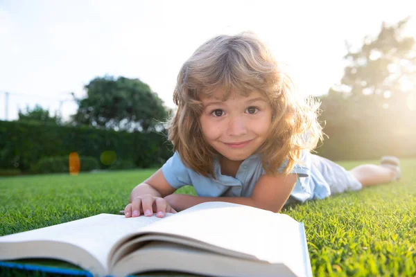 Hij las het boek. Kinderschool en buitenonderwijs. Natuur en park. Vroeg leren. Zomer buiten. — Stockfoto