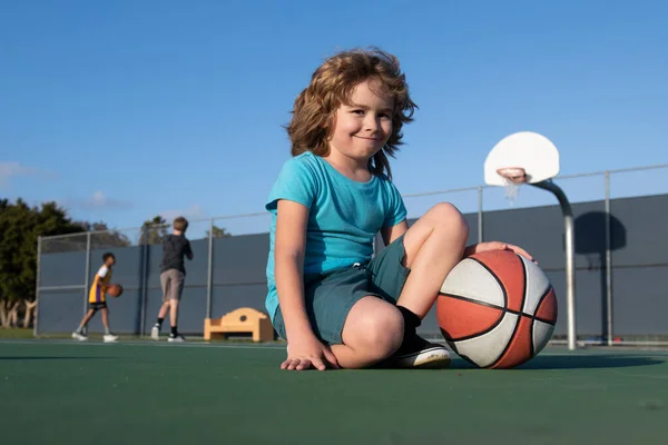 Szczęśliwy mały chłopiec bawiący się w koszykówkę na placu zabaw. — Zdjęcie stockowe