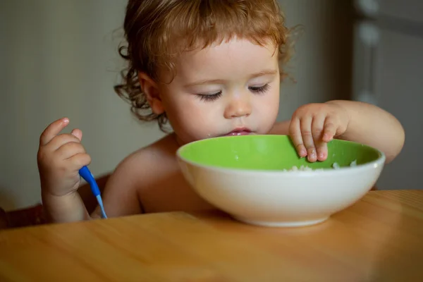 Enfant bébé manger de la soupe dans la cuisine avec de la vaisselle et une cuillère. — Photo