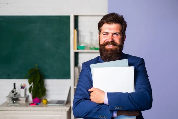 Profesor sonriente parado frente al estudiante de enseñanza de pizarra en el aula. Profesor de escuela guapo en el aula. — Foto de Stock
