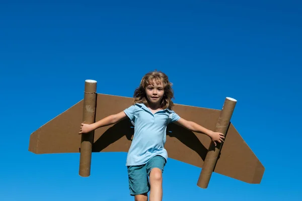 夏の空を背景にしたおもちゃの翼で遊ぶ幸せな子供。子供の成功、指導者と勝者の概念. — ストック写真