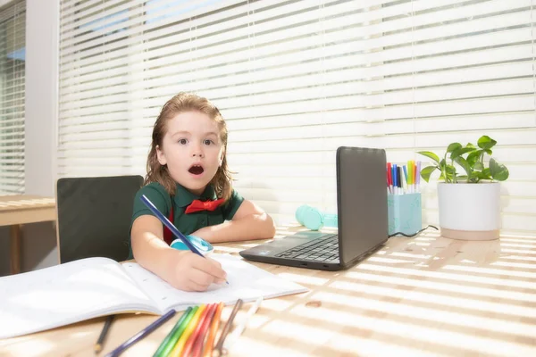 Rapaz excitado faz trabalhos de casa na aula da escola. Escreve texto de notebook laptop. — Fotografia de Stock