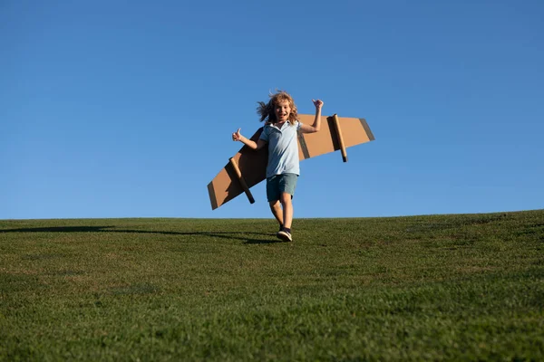 Niño saltando y corriendo con alas de avión de juguete. Sueño con ser piloto. Superhéroe volando. — Foto de Stock