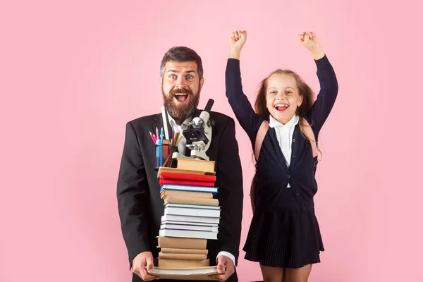 Vater oder Lehrer halten große Stapel Schulhefte in der Hand. Zurück zur Schule, Schülerin mit Uniform. Kleines Mädchen mit einem Stapel Bücher. Schwer zu studieren. — Stockfoto