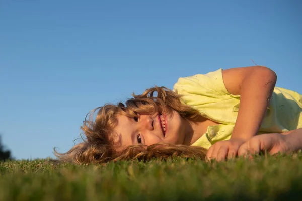 Retrato de un niño feliz sonriente jugando en el campo de hierba al aire libre. Niña riéndose. Expresiones faciales. — Foto de Stock