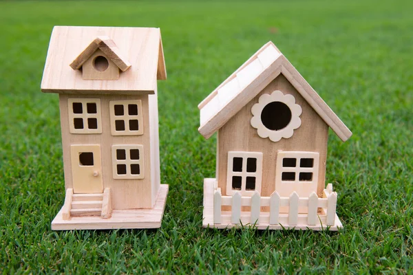 Concepto de casa de vecinos. Juguete casa modelo en el medio de un gran campo de prado de hierba. Pago hipotecario, patio grande. — Foto de Stock