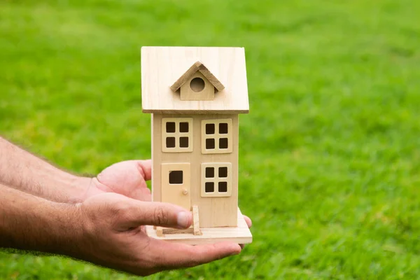Mano sosteniendo el modelo de casa de cerca. Pequeña casa de juguete en miniatura. Hipoteca propiedad sueño mudanza casa y concepto de bienes raíces. — Foto de Stock
