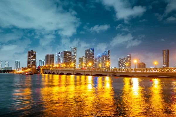 Miami, Florida City na Biscayne Bay. Panorama za soumraku s městskými mrakodrapy a mostem přes moře s reflexí. — Stock fotografie