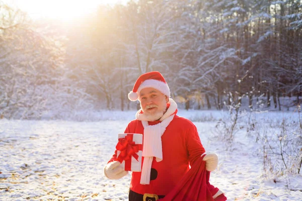 Santa Claus sonriente con regalo en Nochebuena afuera. —  Fotos de Stock