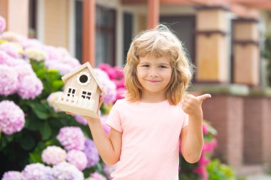 Ev bahçesinde küçük ev modeliyle oynayan sevimli bir çocuk. Çocuk bahçesinde ekoloji bölümü arka bahçeye karşı..