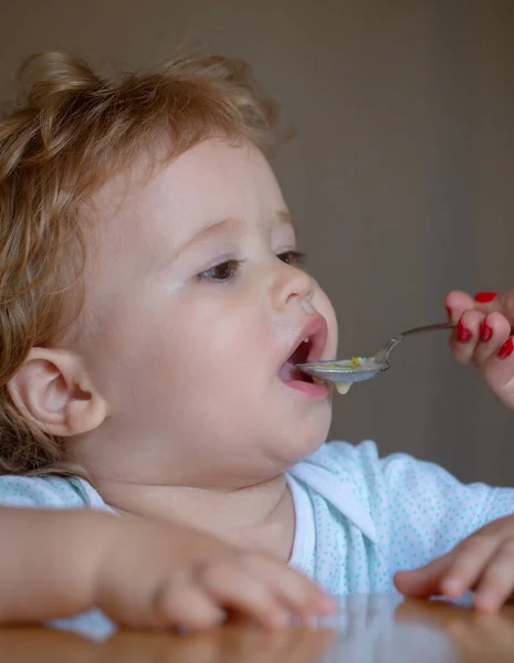 Moeder voedt baby met lepel. Het geven van fruitsaus aan kleine jongen. — Stockfoto