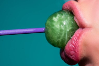 Şeker yalıyorum. Lolipop modeli. Kadın dudakları şeker emiyor. Kırmızı dudaklı çekici manken eşofman altı yiyor lolipop.