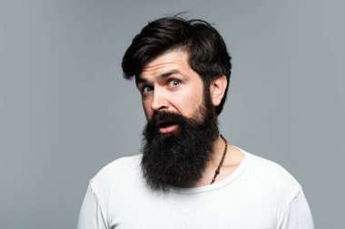 Şaşırmış yakışıklı sakallı adam. Erkek saç kesimi, modern saç stili. Uzun saçlı erkek modelin yakın portresi. Sağlık ve saç bakımı kavramı.