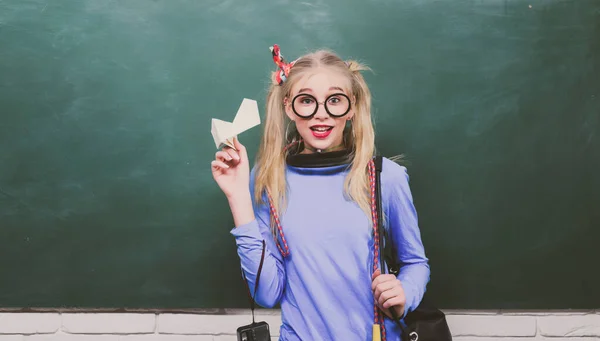 Retrato de una estudiante adolescente. Escuela adolescente chica sosteniendo mochila y papel plano, de pie contra pizarra. —  Fotos de Stock